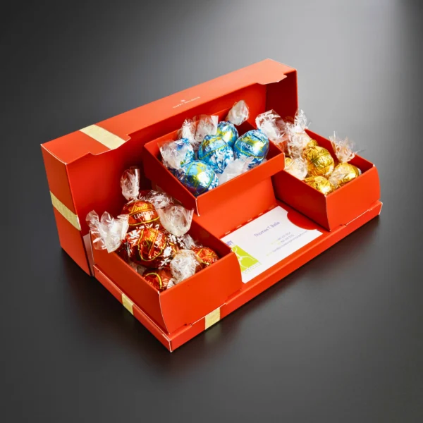 A colorful chocolate gift box featuring assorted Lindor truffles displayed in an elegant red packaging with a gold ribbon.