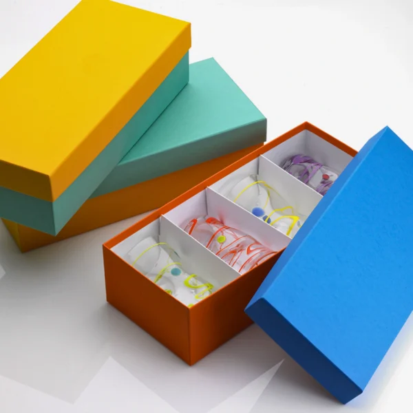 Colorful rigid gift boxes stacked with an open orange box revealing decorative contents.