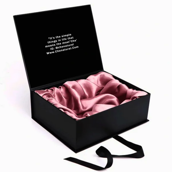 Open black wig box with pink satin interior and printed quote inside.