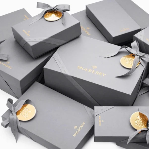 A collection of gray luxury gift boxes adorned with gold ribbons and embossed seals, offering a refined presentation.