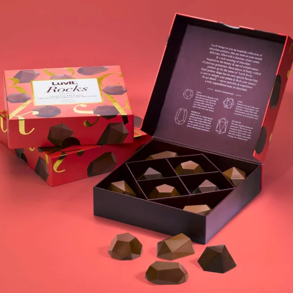 A uniquely designed chocolate box containing geometric chocolate pieces, opened to reveal the treats inside.