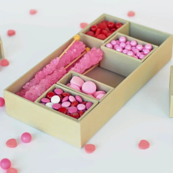 A pastel-colored candy box containing a variety of pink and red sweets displayed in a simple elegant design.