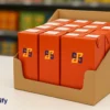 A display of shelf-ready packaging boxes in orange color, branded with the Box Printify logo, arranged in a retail setting to enhance visibility and accessibility.